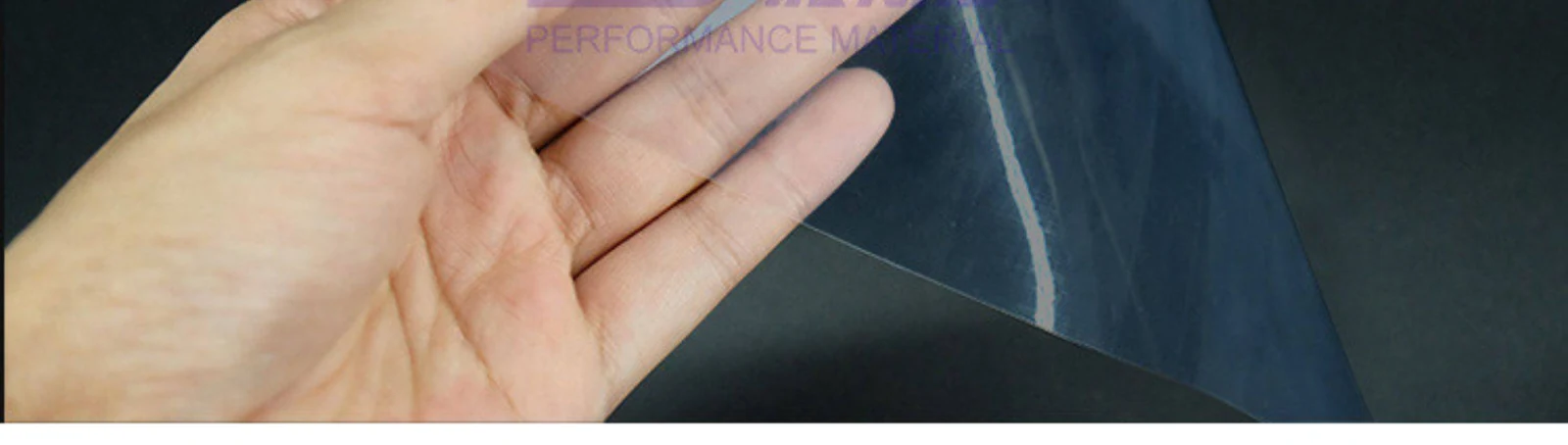 A hand holding a thin clear fluoropolymer film
