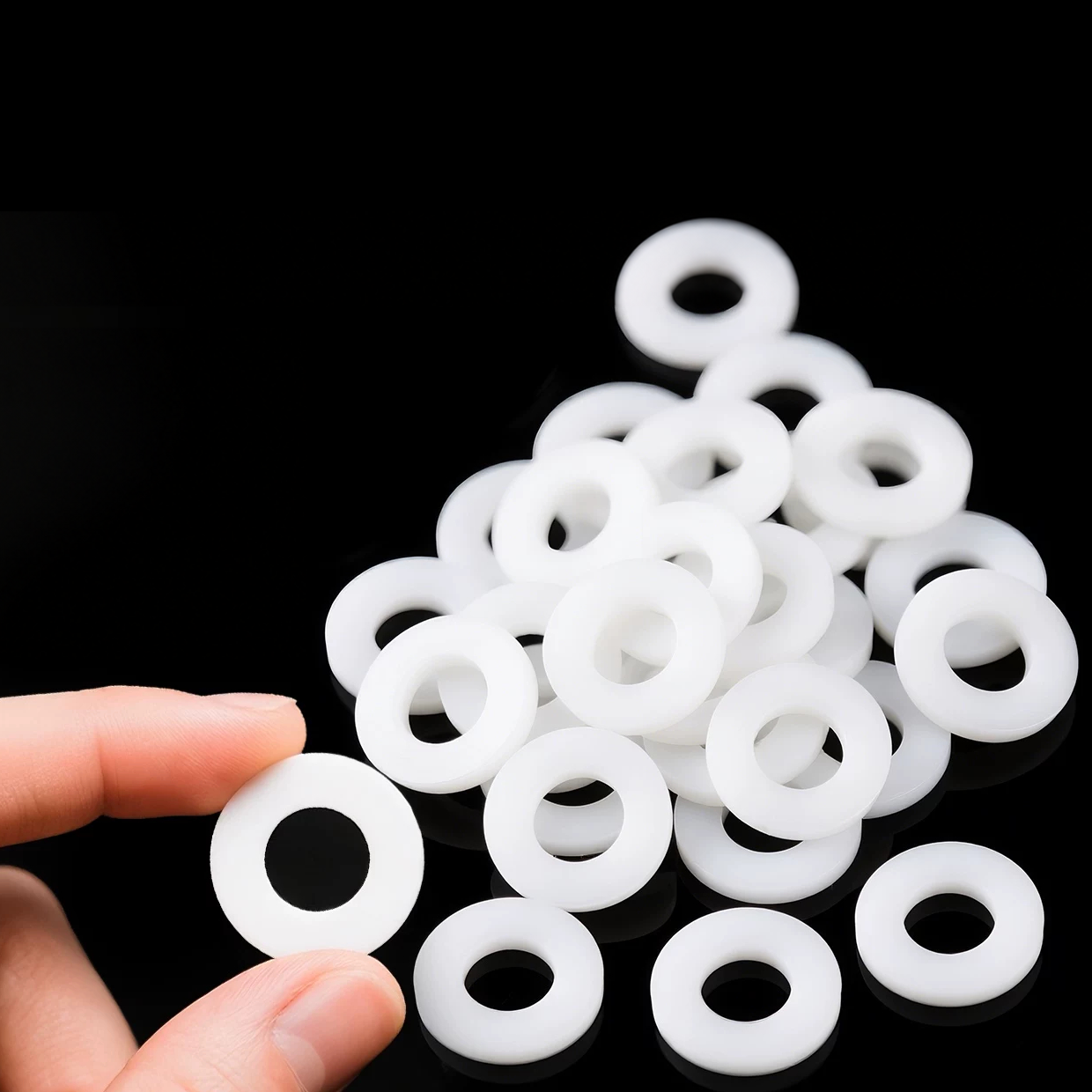 A hand holding a PTFE sealing washer beside a group of closed rings