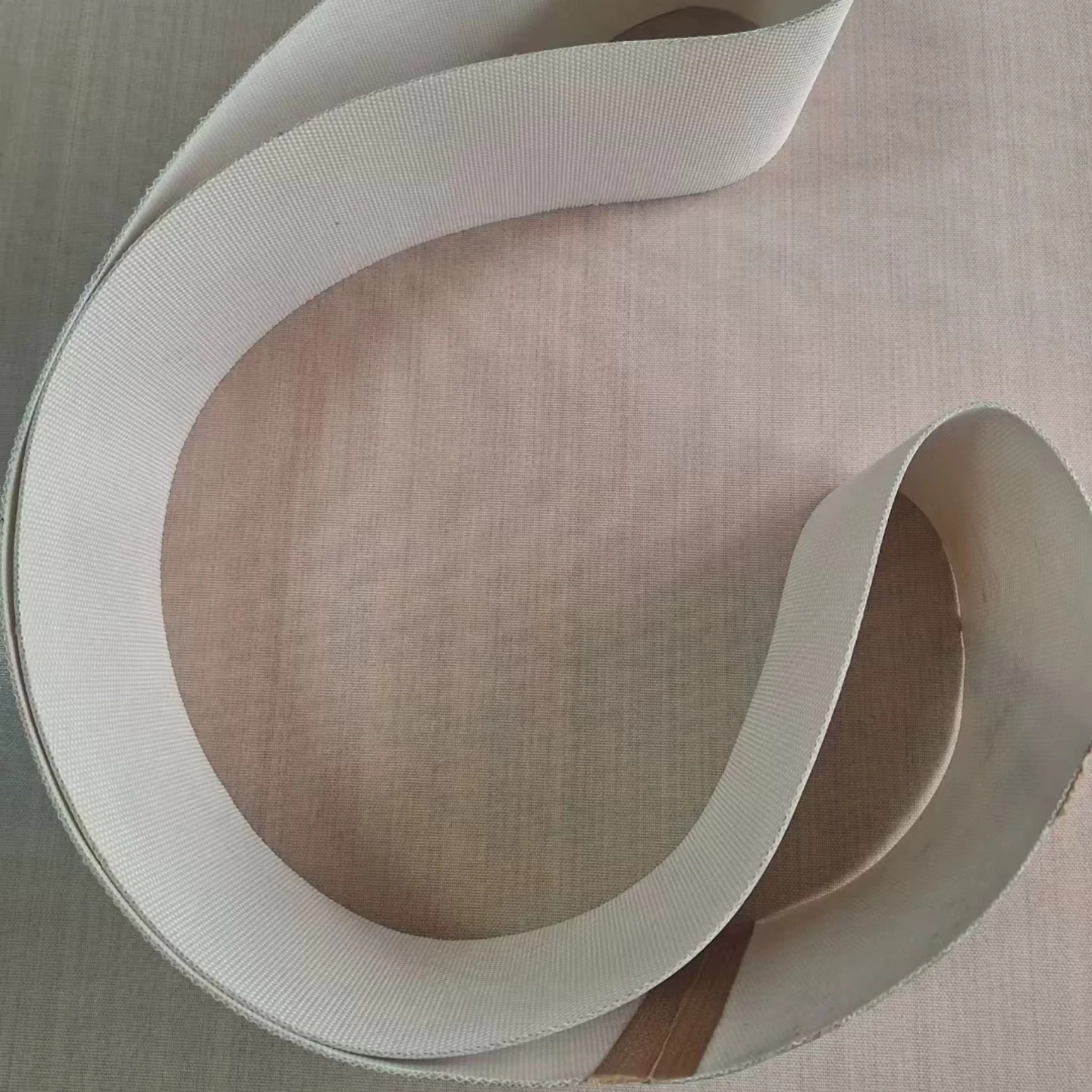White solid PTFE coated fabric belt in a curved loop