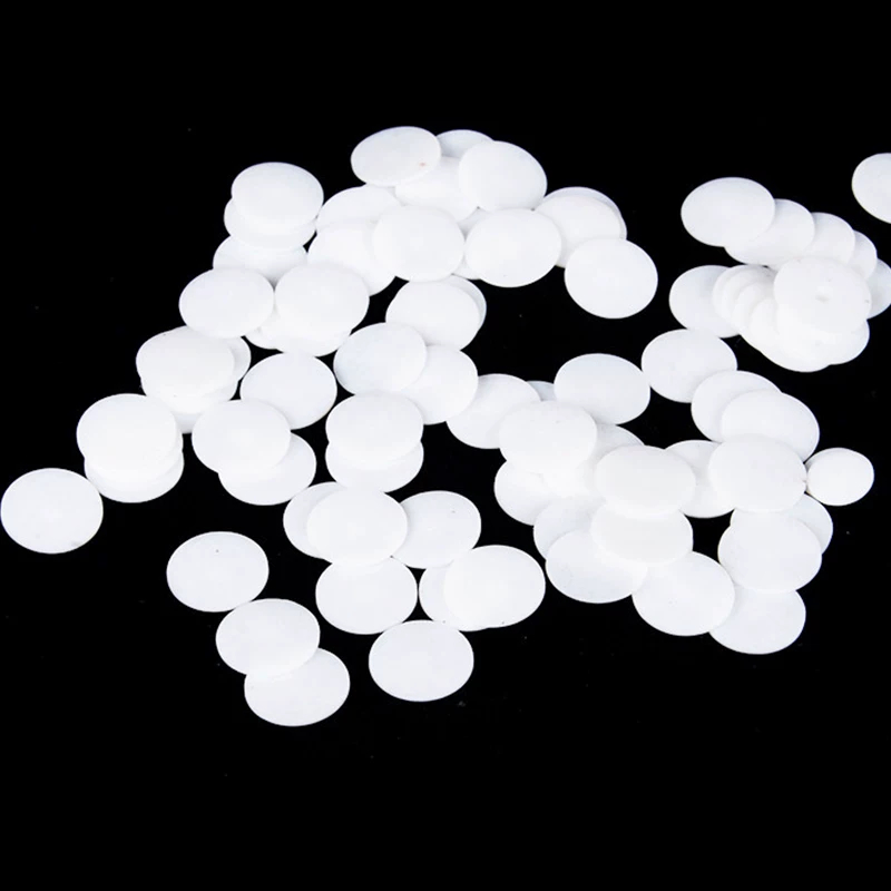 Flat white PTFE circular blanks laid out on a dark surface